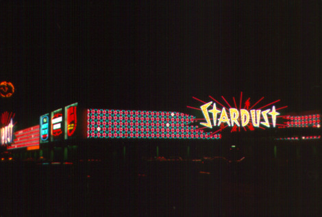 Photograph of color-changing neon signs on the front and side exteriors of the Stardust Hotel and Casino (Las Vegas), 1969